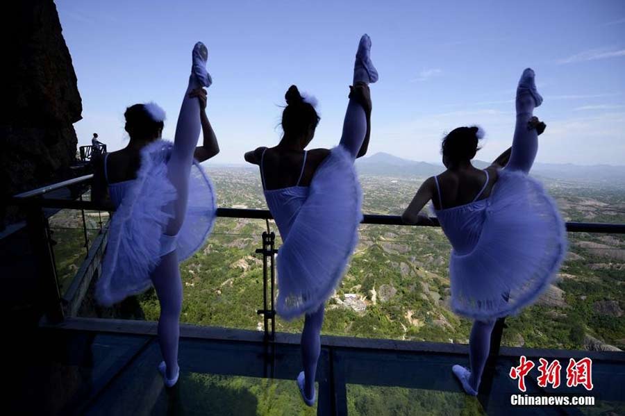 Dancers perform ballet on cliff, glass walkway