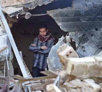 An Iraqi man surveys the ruins of a destroyed house in Falluja the morning after a U.S. air strike October 22, 2004. [Reuters]