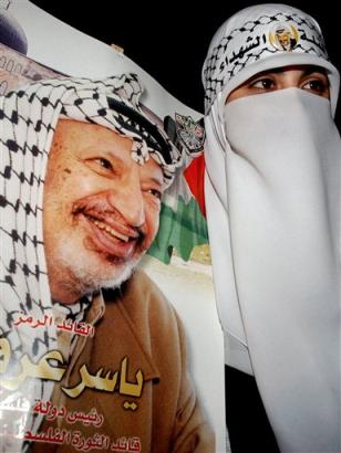 A member of Yasser Arafat's Fatah movement holds a poster of the ailing Palestinian leader during a pro-Arafat demonstration in the West Bank town of Nablus Sunday Nov. 7, 2004. Critically ill, Arafat spent a fifth day Sunday in the intensive care unit of a French military hospital in Paris, an aide said, as Israeli officials completed plans for a burial in the Gaza strip in the event of his death. [AP]