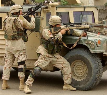 U.S. troops take cover after they came under fire following a car bomb which rammed into a civilian convoy along Baghdad's airport road, setting vehicles on fire, Wednesday Nov. 17 2004. The stretch of highway leading to Baghdad's international airport is considered one of the country's most dangerous roads. [AP]