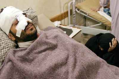 An Iraqi woman sits next to her husband who was injured in a suicide car bomb attack, which targeted the police station where he works in the southern city of Basra, January 10, 2005. At least one suicide bomber was killed and seven people, four of then policemen, were wounded in two separate car bombings in the southern Iraqi city of Basra on Monday, hospital sources and eyewitnesses said. Picture taken January 10, 2005. [Reuters]