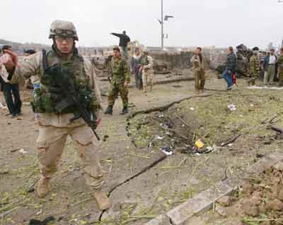 A U.S. Army soldier secures the site of a car bomb attack in Baghdad January 18, 2005. The suicide car bomb exploded on Tuesday at a Baghdad office of the Supreme Council for the Islamic Revolution in Iraq (SCIRI), a party official said, in the latest attack on Shi'ites before Iraq's January 30 election. [Reuters]