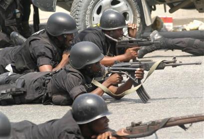 Members of the Haitian National Police drop to the ground and take position after hearing gunshots as supporters of ousted Haitian President Jean-Bertrand Aristide pass during a demonstration calling for his return in Port-au-Prince, Haiti, Thursday, March 24, 2005. (AP Photo/EVENS SANON)