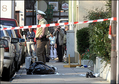 A German policeman stands next to the covered body of a woman killed when a man with a samurai sword ran amok during a service in an evangelical Methodist church in the southern city of Stuttgart.(AFP/DDP/Michael Latz)