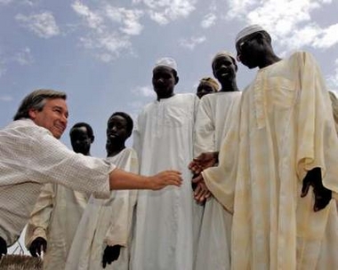 United Nations High Commissioner for Refugees Antonio Guterres (L) shakes hands with internally displaced Sudanese men at the Riyad camp in the western Darfur region of Sudan August 24, 2005.