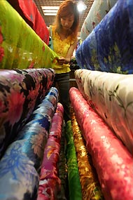 A Chinese shopper checks out cloth at a textile shop in Beijing yesterday.[newsphoto]