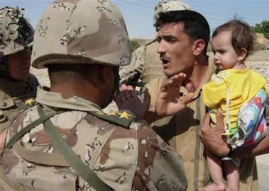 An Iraqi father trying to take his ill child to a hospital in a nearby city talks to U.S. Marines and an Iraqi Army commander Saturday Oct. 8, 2005, in Haditha, Iraq. The man could not reach the hospital after major roads were blocked during the latest offensive by U.S. and Iraqi forces searching for insurgents in western Iraq, but the Marines instructed the man to bring the child to their base for treatment. (AP