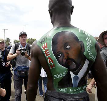 A man with a portrait of Congress of Democratic Change (CDC) candidate in Liberia's presidential elections George Weah painted on his back poses for a photographer in Monrovia October 8, 2005. Tens of thousands of supporters of the Liberian presidential hopeful brought Monrovia to a standstill on Saturday as the millionaire soccer star held a final campaign rally before Liberia's first post-war elections. 