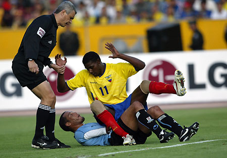 Brazilian referee Marcio Rezende (L) helps Ecuador's Agustin Delgado (R) stand as Uruguay's Dario Rodriguez gestures during 2006 World Cup qualifying soccer match at Atahualpa stadium in Quito, Ecuador October 8, 2005. Ecuador and Uruguay tied 0-0. [Reuters]