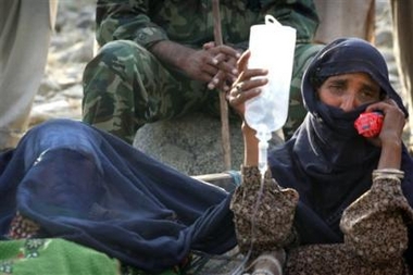 An earthquake survivor holds an IV bag for a loved one as they wait for a helicopter to arrive and evacuate them from a river bank in Balakot, Pakistan Thursday, Oct. 13, 2005. 