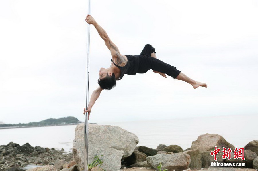 Male pole dancer shows strength and beauty