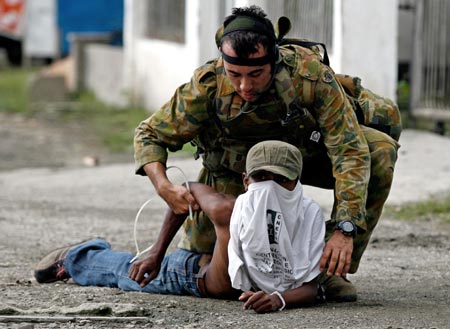 A member of the Australian peacekeeping troops detains a Timorese mob member for setting houses ablaze in East Timor's capital Dili May 28, 2006. 