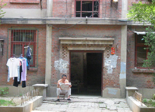 A Chinese man reads newspaper in Juixiaqiao Sub-district in Beijing, June 9, 2007. Local government in Jiuxianqiao and the real estate developer jointly organize the vote on Saturday to see if majority residents of over 5000 families accept the new compensation policy after failed attempts to reach an agreement through other ways. Both notary officials and supervisors are invited to monitor the vote that runs from 9 a.m. to 9 p.m. at six ballot booths. [Sun Yuqing/www.tsdianying02.cn]