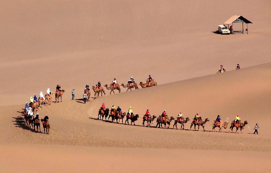 Tourists enjoy themselves at Mingsha Hill desert