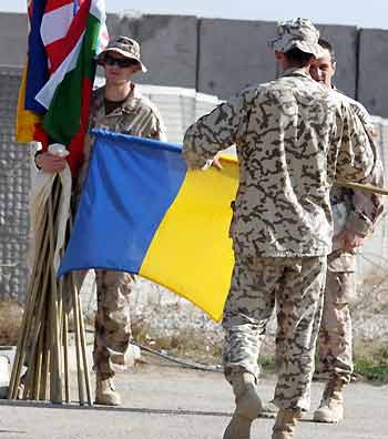 A Ukrainian soldier folds his national flag after a turn-over ceremony in the Iraqi city of Kut, south of Baghdad December 19, 2005. More than 900 Ukrainian troops stationed in Iraq since 2003 are leaving while Polish, Romanian and Kazakhstan soldiers take over the camp in Kut.