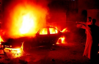 Iraqi men spray water onto the burning car owned by Ahmed Ali al-Yasin, the brother of Asaad Ali al-Yasin the head of Samarra city council, after he was injured with his son Othman Ahmed Ali, by the explosion from a timed-bomb attached to the car, in the city of Samarra, Iraq, on Monday, June 12, 2006. [AP]