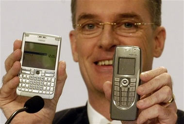 Simon Beresford-Wylie, CEO-designate of Nokia Siemens Networks, poses with mobile phones during a press conference in Frankfurt, Germany, Monday, June 19, 2006. Siemens and Nokia Corp. said Monday they will combine their mobile network operations to create a joint venture with annual revenues of 15.8 billion euro (US$20 billion), a move that will help them compete with market leader Ericsson AB. (AP Photo