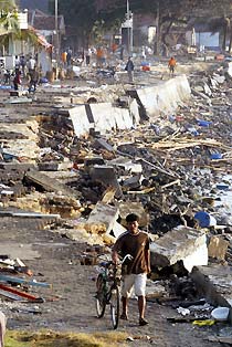 A man wheels his bicycle past the devastated area of Pangandaran, Indonesia July 18, 2006. 