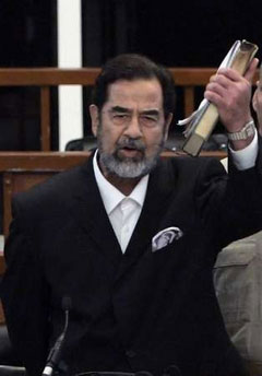 Former Iraqi president Saddam Hussein holds a holy Koran in his hand as he reacts to the verdict during his trial held under tight security in Baghdad's heavily fortified Green Zone November 5, 2006. A U.S.-backed Iraqi court on Sunday sentenced toppled leader Saddam Hussein to death by hanging for crimes against humanity. 