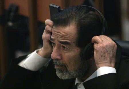 Ousted Iraqi leader Saddam Hussein adjusts his headphones as he listens to witness testimony during his trial in Baghdad's heavily fortified Green Zone October 17, 2006. 