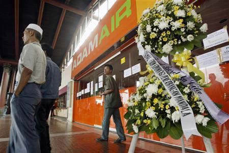 Men stand near a condolence wreath at an Adam air counter in Jakarta airport, January 3, 2007. REUTERS/Crack Palinggi