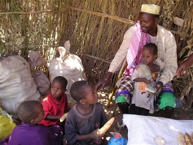 A father feeds his children with bread in a makeshift house after he escaped from Mogadishu to Afgoiye, Friday, Feb. 23, 2007. Uganda's top defense officials have arrived in Somalia ahead of a planned African Union peacekeeping deployment, a day after Islamic extremists threatened suicide attacks against Ugandan and other foreign troops, officials said Friday. (AP