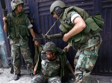 An wounded Lebanese soldier on the ground receives help from his colleagues after he was injured in clashes with fighters from an Islam militant group, in the north city of Tripoli, Sunday May 20, 2007. 